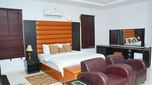 A bedroom with a bed, a desk, a chair, and a TV. - 3A Lodge (Lekki)