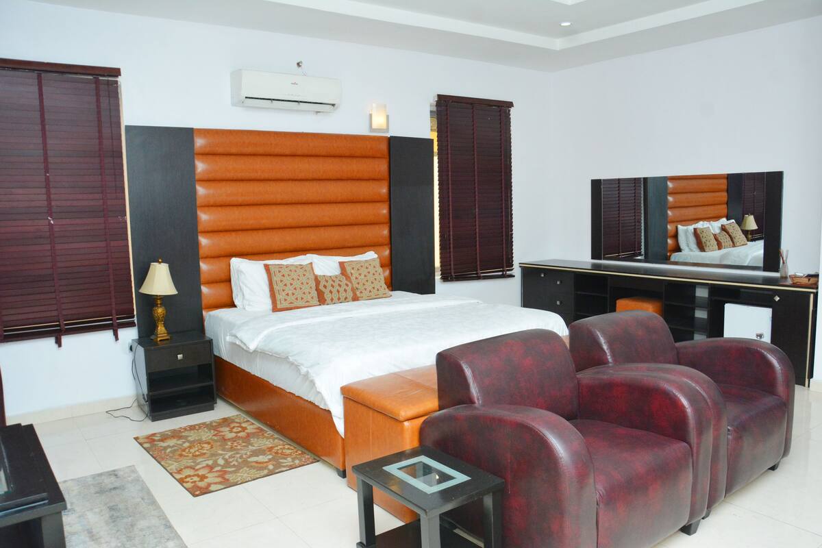 A bedroom with a bed, a desk, a chair, and a TV.