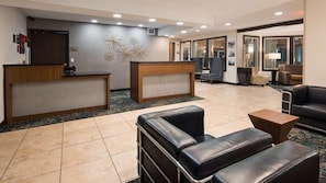 A hotel lobby with a reception desk, seating area, and a large window.