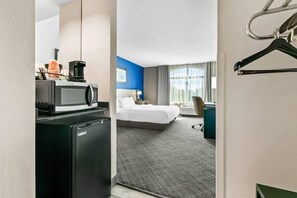 A hotel room with a bed, a desk with a computer, a microwave, and a refrigerator. - Comfort Inn & Suites Grand Blanc/flint (Grand Blanc)