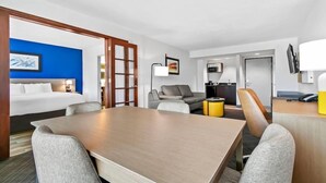 Habitació d'hotel amb llit, taula de menjador, sofà, televisió i escriptori amb telèfon.