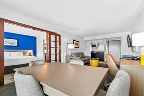 Une chambre d’hôtel équipée d’un lit, d’une table à manger, d’un canapé, d’une télévision et d’un bureau avec un téléphone.