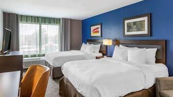 A hotel room with two beds, a desk, and a chair.