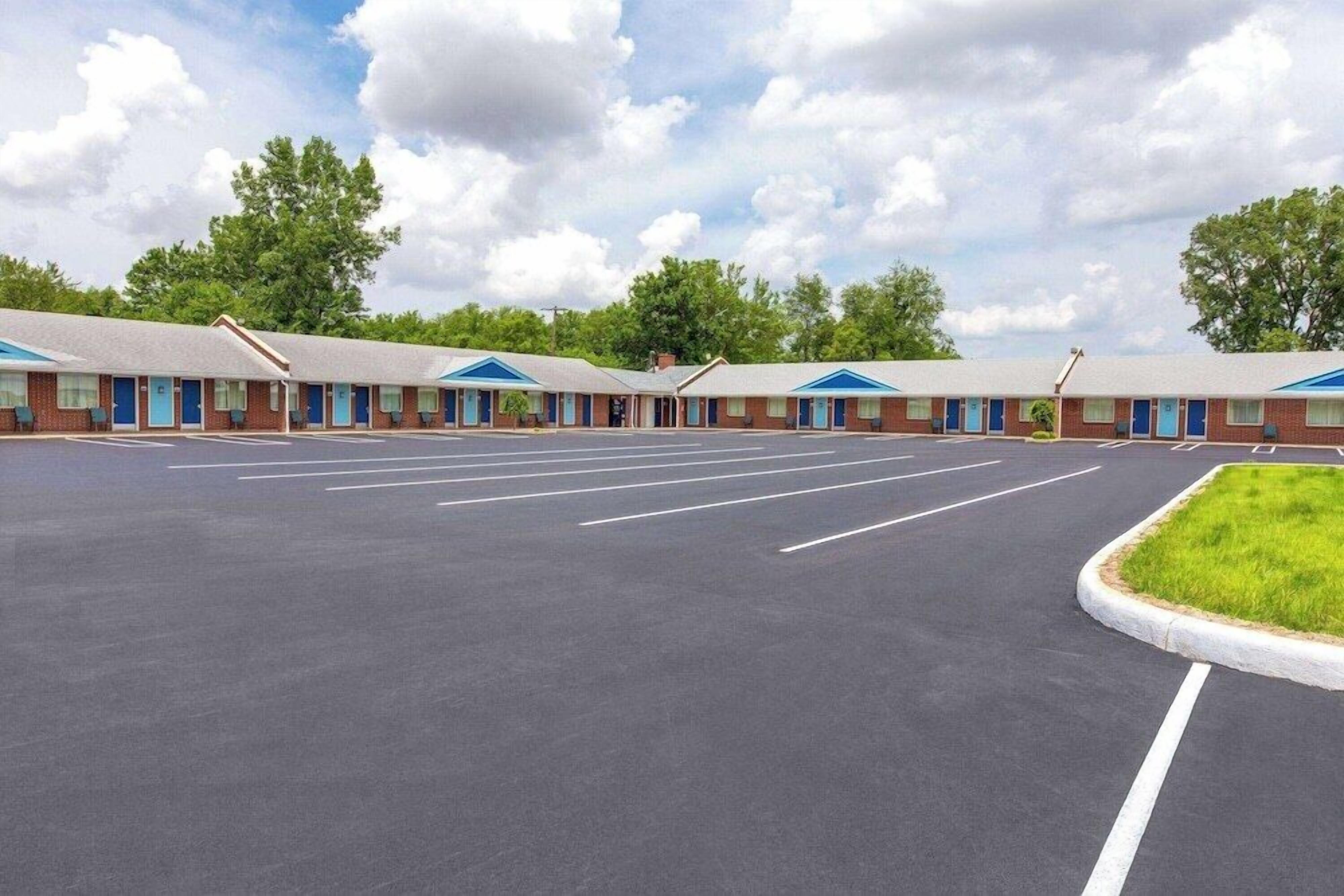 A motel with multiple rooms, a parking lot, and a grassy area.