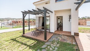 A house with a patio area featuring a pergola and a small table with chairs.