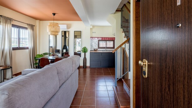 A modern living room with a sofa, dining table, and kitchen area.