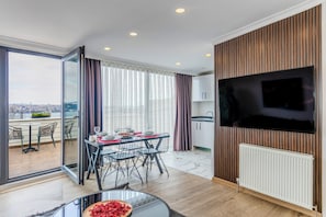 A modern living room with a dining area, a large TV, and a city view. - Etiz Hotels & Residences (Istanbul)