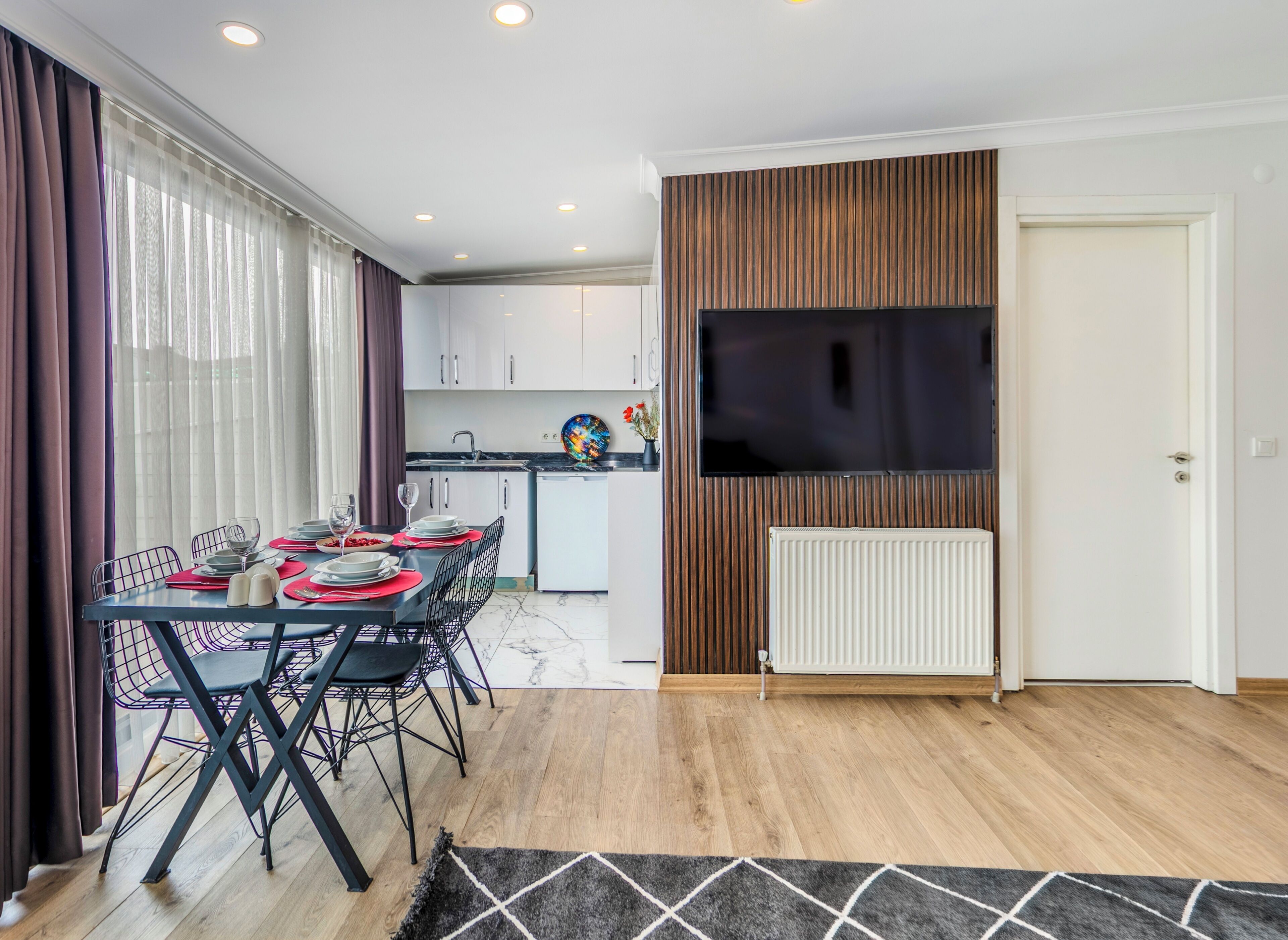 A modern kitchen with white cabinets, a black countertop, and a built-in TV.