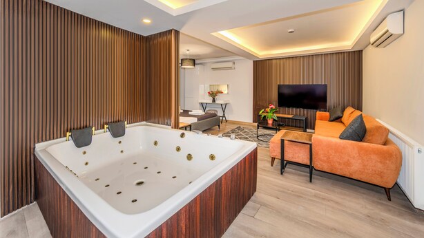 A modern living room with a large white bathtub, a sofa, a TV, and a fireplace. - Etiz Hotels & Residences (Istanbul)