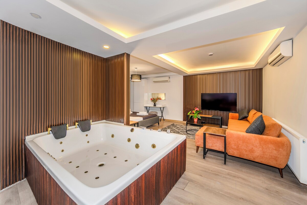A modern living room with a large white bathtub, a sofa, a TV, and a fireplace.