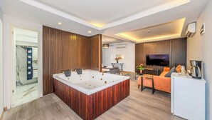 A modern living room with a central hot tub, a sofa, a coffee table, and a TV. - Etiz Hotels & Residences (Istanbul)