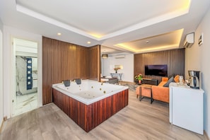 A modern living room with a central hot tub, a sofa, a coffee table, and a TV. - Etiz Hotels & Residences (Istanbul)
