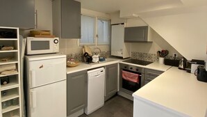 A compact kitchen with a microwave, refrigerator, dishwasher, oven, and a sink. - RIVE GAUCHE - RIVOLI/LOUVRE Type 3/4 approx. 100m2 in absolute calm (Paris)