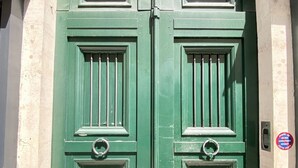 A double green door with a metal handle and a keyhole, set in a stone building with a tiled ground. - RIVE GAUCHE - RIVOLI/LOUVRE Type 3/4 approx. 100m2 in absolute calm (Paris)