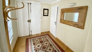 A hallway with a patterned rug, white doors, a wooden mirror, and a wall-mounted light fixture. - RIVE GAUCHE - RIVOLI/LOUVRE Type 3/4 approx. 100m2 in absolute calm (Paris)