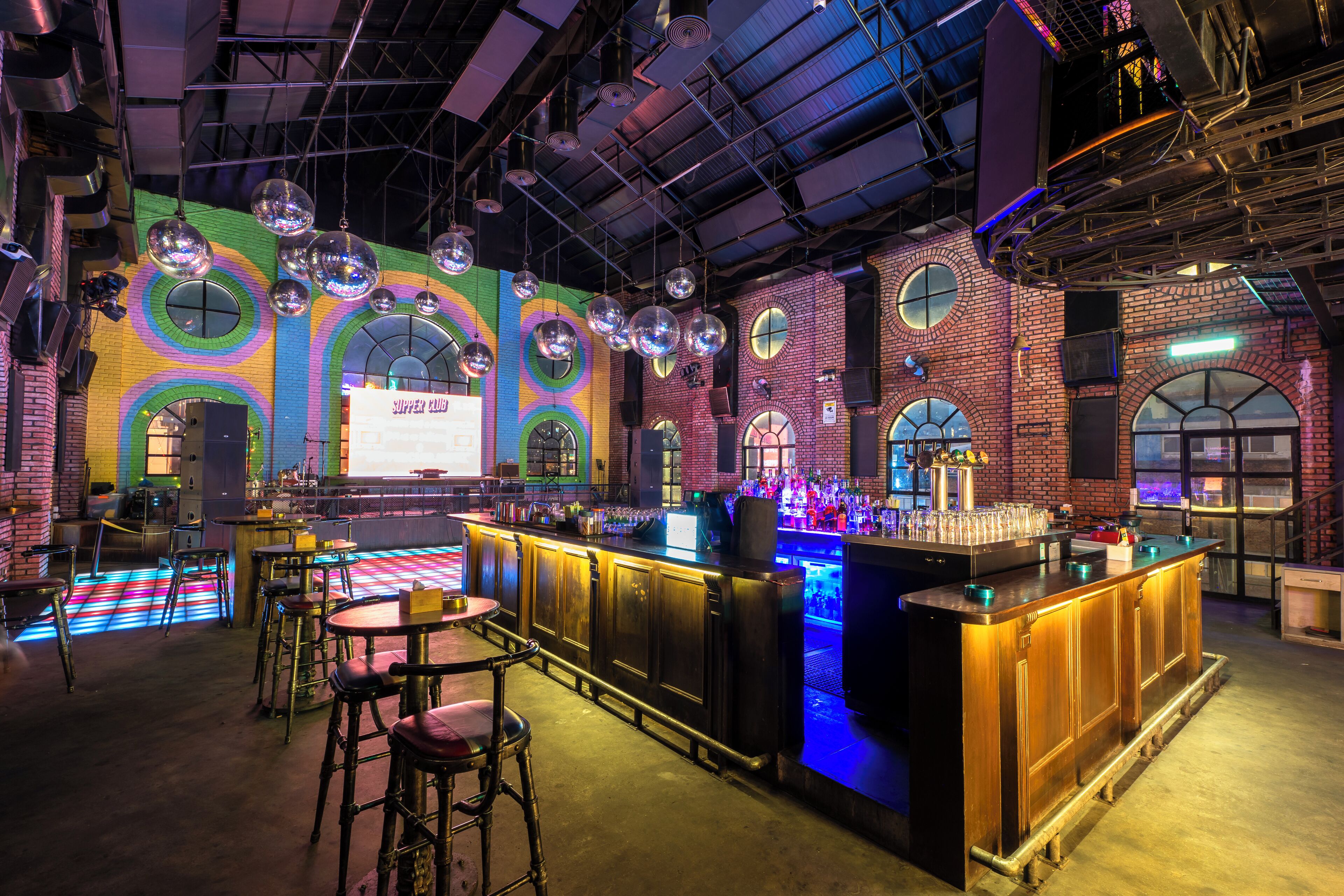 A bar area with a bar counter, stools, and disco balls.
