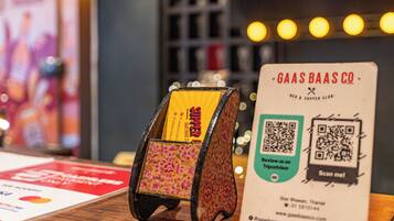 A wooden display stand with a floral design, a QR code, and a sign for 'GAAS BAAS CO - Bed & Supper Club'.