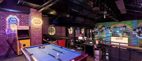 A pool table in a dimly lit room with a brick wall and neon signs.