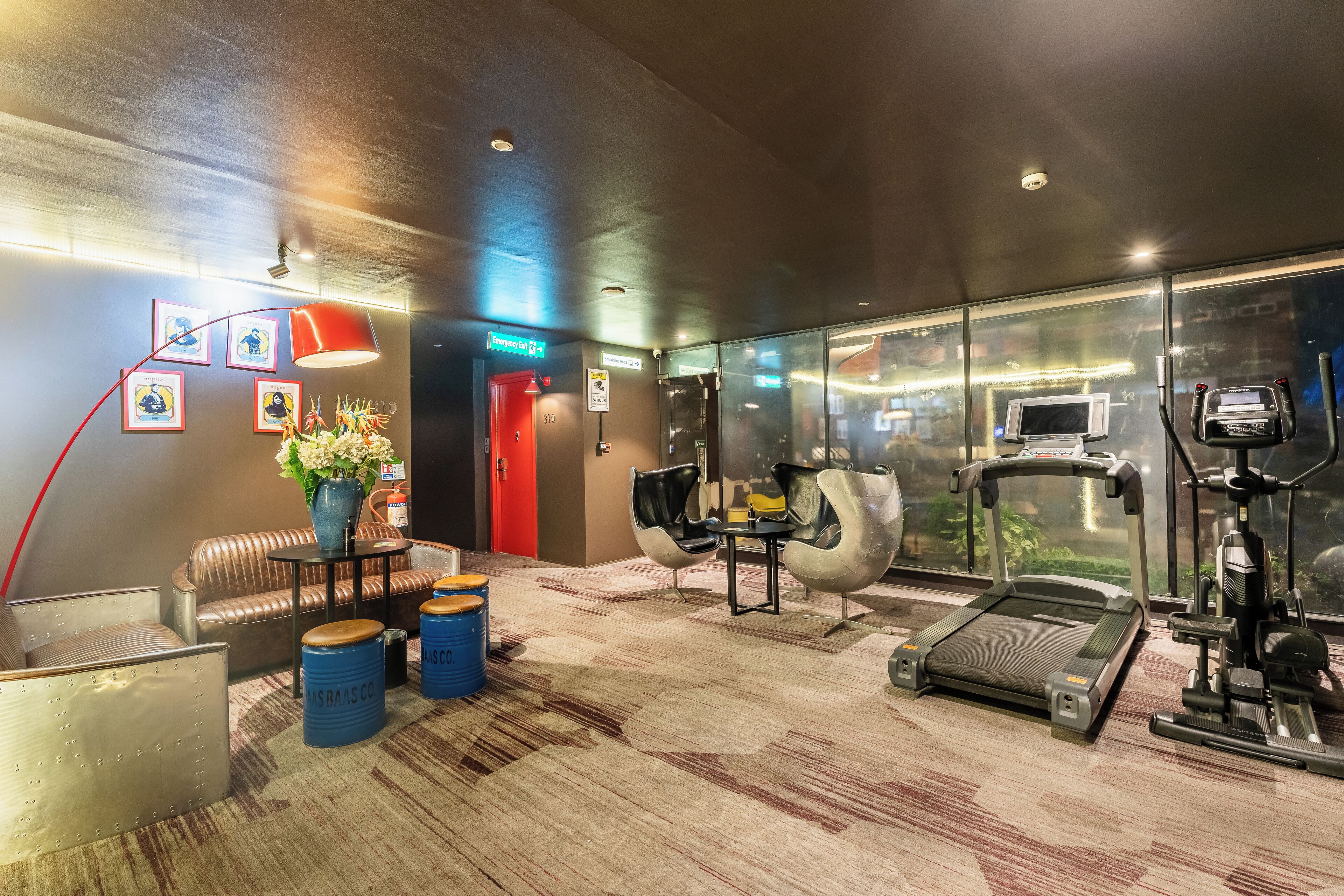 A modern gym with a treadmill, exercise bike, and mirrored walls.