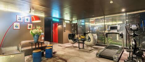 A modern gym with a treadmill, exercise bike, and mirrored walls.