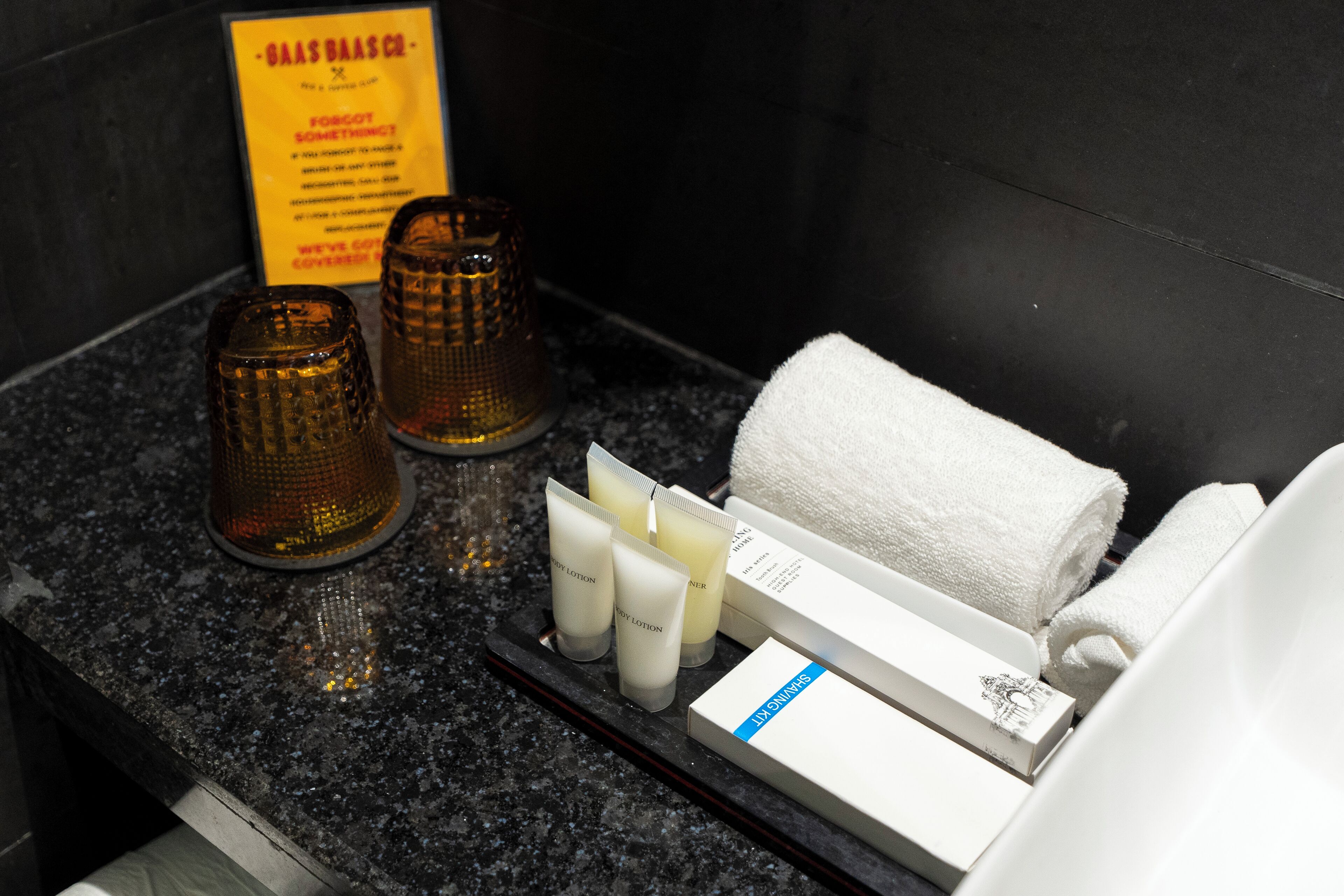 Una encimera de baño con artículos de aseo, una toalla y un cartel.