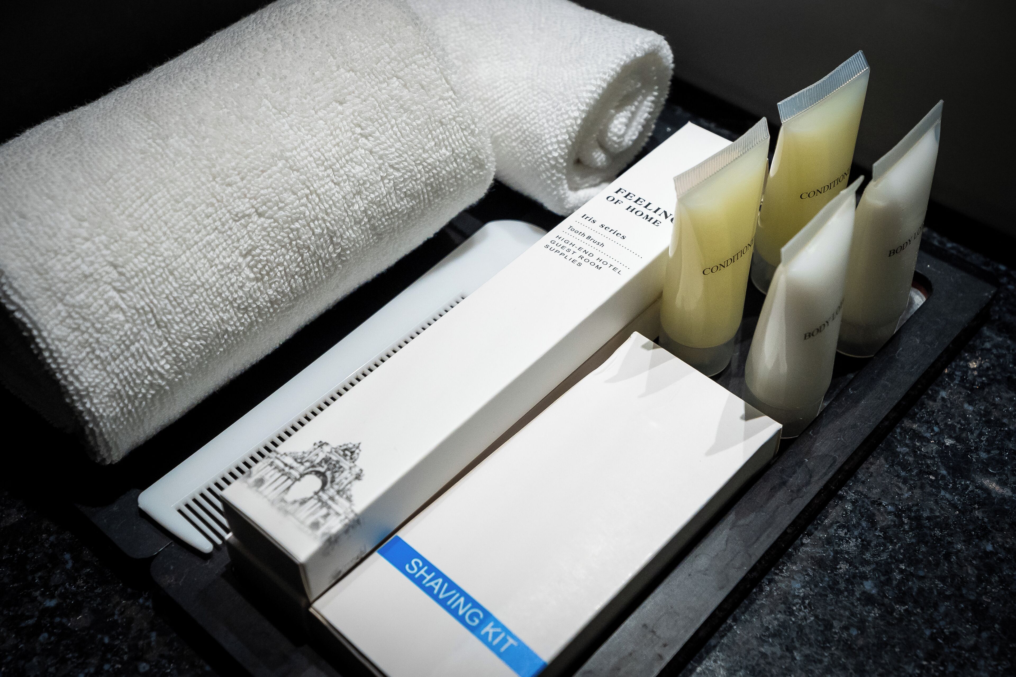 A bathroom with a towel, shaving kit, and toiletries.