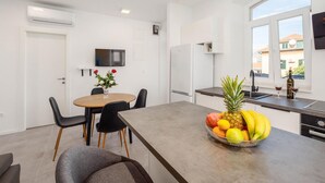 A modern kitchen with a dining area, a fruit bowl on the counter, and a TV mounted on the wall. - Stunning apartment in Split with WiFi (Split)