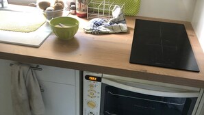 Een compacte keuken met een ingebouwde oven, een magnetron en een klein spoelgedeelte.