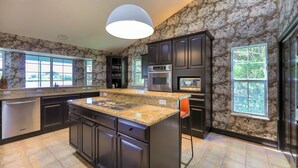 A modern kitchen with granite countertops, stainless steel appliances, and dark cabinetry. - Sanibel Sunrise - Bayfront home, short walk to the beach! (Sanibel)