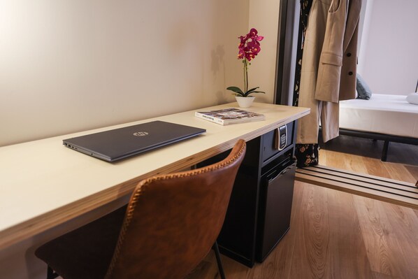A small workspace with a laptop, a book, and a potted orchid on a wooden desk. - Mythic Valencia Hotel (Valencia)