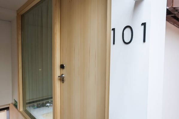 A wooden door with a glass panel and a door handle. The number "101" is visible on the wall to the right of the door. - Mythic Valencia Hotel (Valencia)