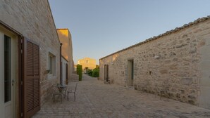 A narrow cobblestone street flanked by stone buildings with shuttered windows and doors. - Rosemary - open space in the Hyblean countryside (Sicilia)