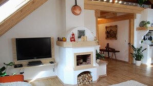 Un soggiorno con televisore, camino e travi in legno.