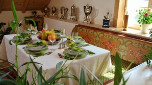 Un tavolo da pranzo apparecchiato con piatti, bicchieri e posate, circondato da piante verdi.