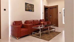 Un salon moderne avec un canapé en cuir rouge, une table basse en verre et un tapis à motifs.