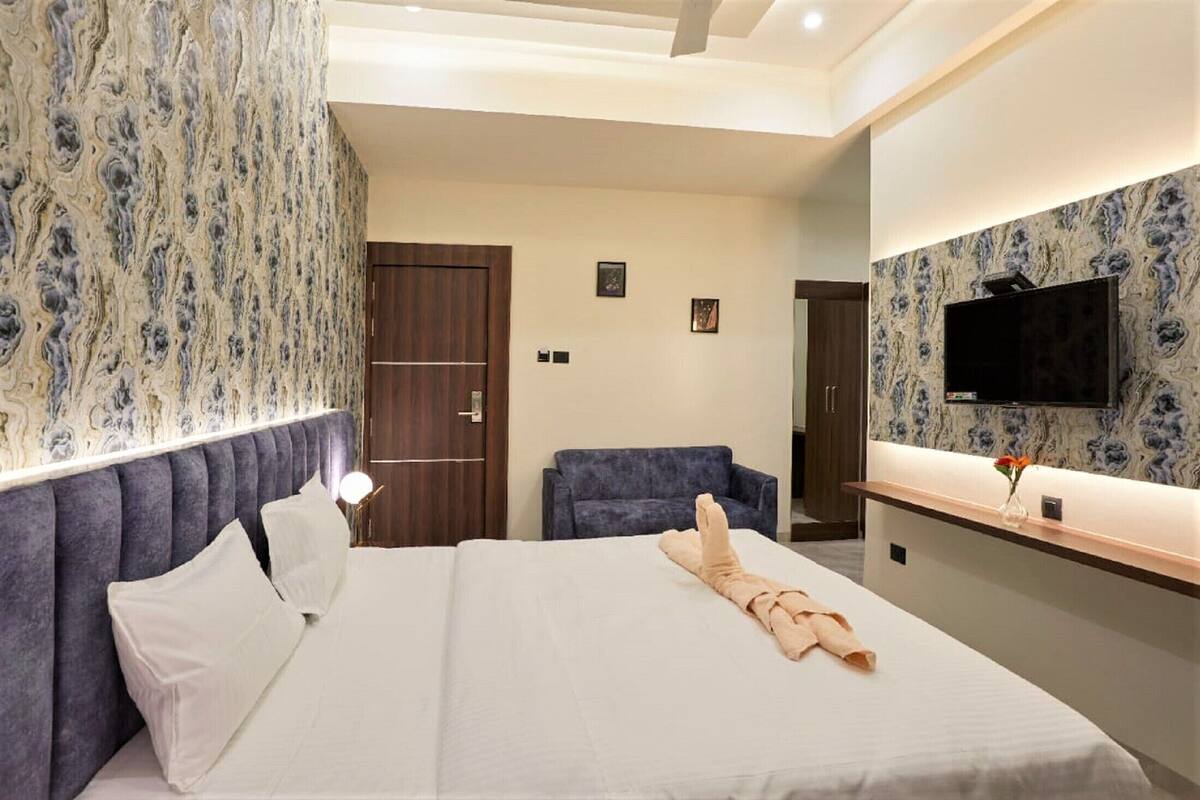 Una habitación de hotel con una cama, una silla, un televisor y un espejo.