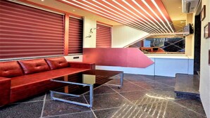 Un intérieur moderne avec un canapé rouge, une table en métal et un escalier menant à un balcon.
