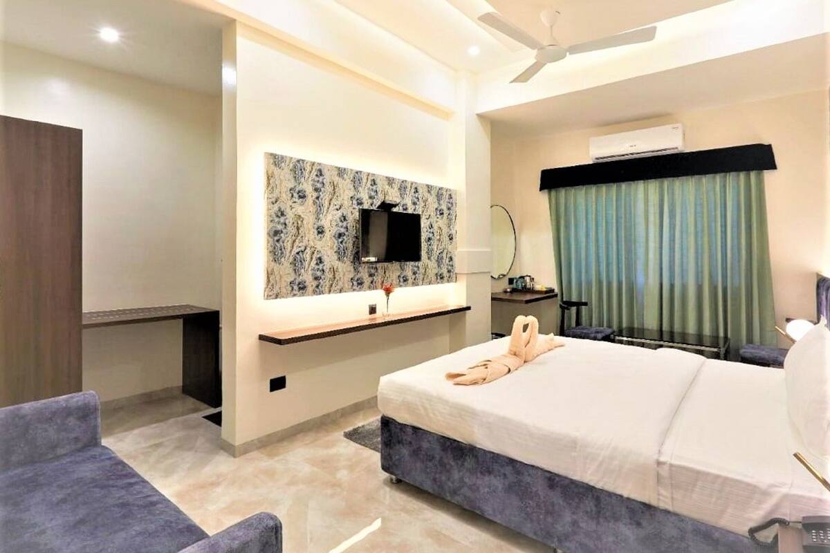Una habitación de hotel moderna con cama, escritorio, televisor y ventilador de techo.