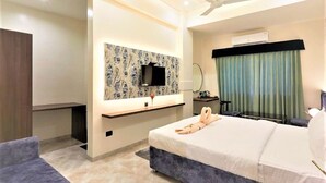 Une chambre d’hôtel moderne équipée d’un lit, d’un bureau, d’une télévision et d’un ventilateur de plafond.