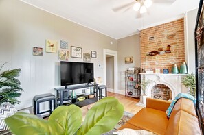 A living room with a TV, sofa, and fireplace.