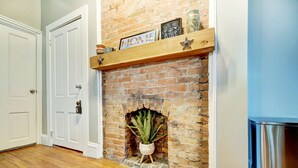 A brick fireplace with a shelf above it holding decorative items. - Modern Rustic Charm with City Views (Cincinnati)
