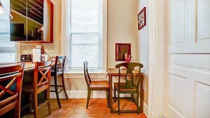 A dining area with wooden chairs and a table, a window with blinds, and a wall-mounted cabinet. - Modern Rustic Charm with City Views (Cincinnati)