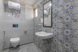 A bathroom with a white toilet, a white sink, and a shower. - Deluxe Double Room with Balcony (Jaipur)
