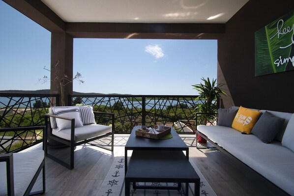 A balcony with a sofa, chairs, and a table, overlooking a body of water.