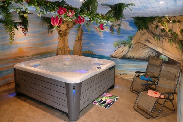 A hot tub in a room with a tropical mural, a chair, and a small mat. - "Sommerberg" 4-star vacation apartment, including the Schwarzatal guest card (Rohrbach)