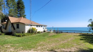Una casa de un solo piso con techo inclinado, patio cercado y vista al océano.