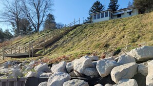 Una ladera con rocas grandes y una escalera de madera que sube hacia una casa.
