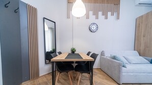 Een moderne woonkamer met een houten eettafel, zwarte stoelen, een grijze bank en een hanglamp.