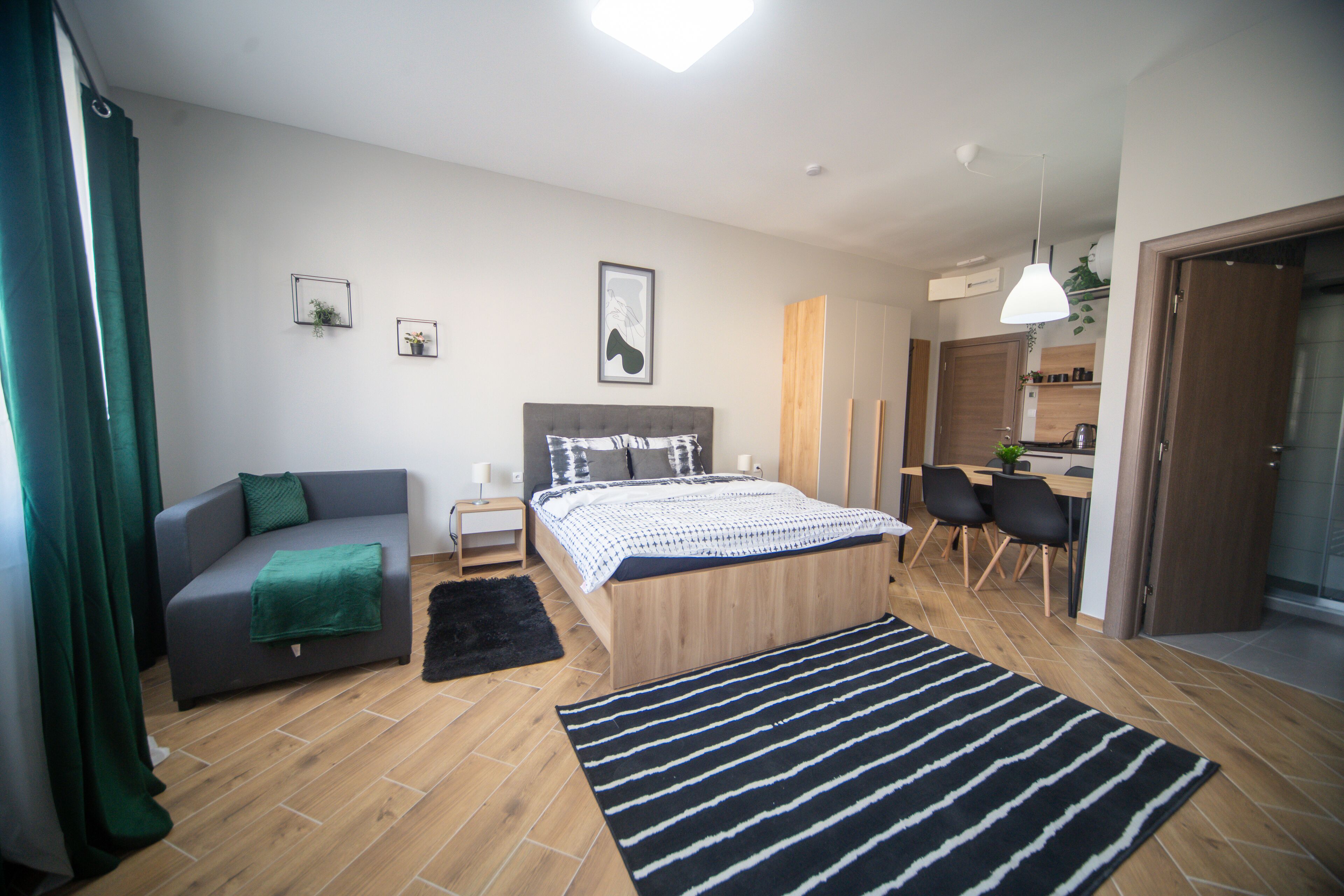 A modern bedroom with a bed, a sofa, a desk, and a dining area.