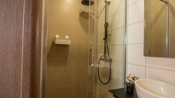 A modern bathroom with a glass-enclosed shower, a wooden vanity with a white sink, and a mirror above the sink.